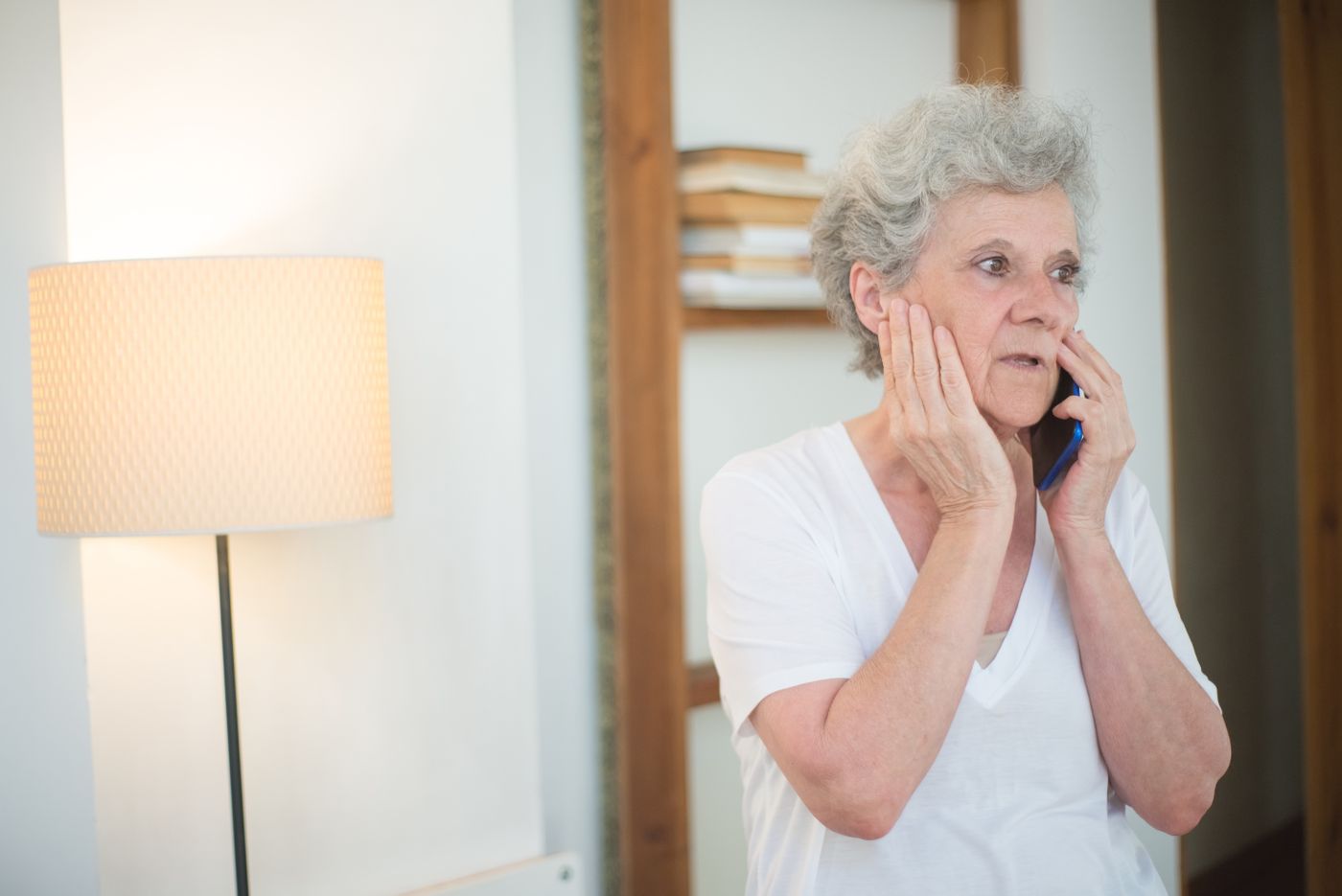 Elderly woman looking worried while receiving a possible scam phone call